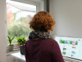 Eine Frau steht vor einem Schreibtisch - Pflanzen sind auf der Fensterbank