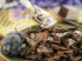 Bruchstücke von Zwetschgenschokolade mit zwei blauschwarzen Früchten