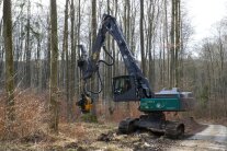 Ein Raupenharvester steht neben einer Forststraße zur Holzernte bereit.