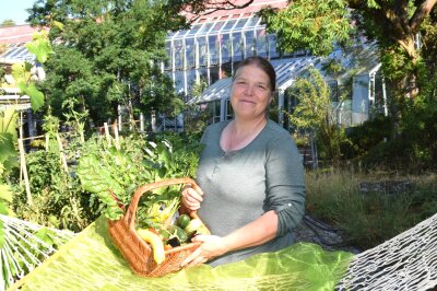Ein Frau steht hinter einer Hängematte, in der Hand ein Korb mit Gemüse