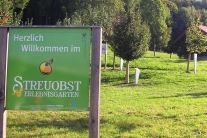 Eingangsschild Streuobserlebnisgarten mit Bäumen im Hintergrund