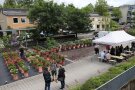 Besucher stehen vor die Kübelpflanzen mit blühenden Blumen, nebenan steht einen Faltpavillons