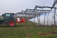 Heißnebelgerät am Schlepper angehängt, hintere Behälter mit Nebel auf Obstbäumen besprüht.