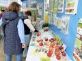 Besucher vor einem Tisch und einer Wand mit Informationen über die Vielfalt des Streuobstes