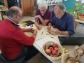 Zu sehen sind 3 Männer an einem Tisch sitzend, die Äpfel zur Sortenbestimmung begutachten. 