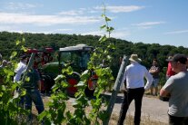 Mehrere Leute stehen um einen Weinbergschlepper mit angebautem Gerät im Weinberg