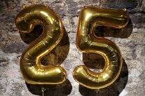 Zwei goldene Luftballons stellen die Zahl 25 dar.